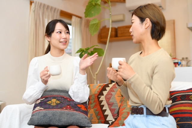 ソファに座ってお茶を飲みながら話をする女性2人。