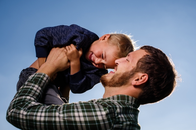 笑っている子どもを抱っこしている笑顔の父親。